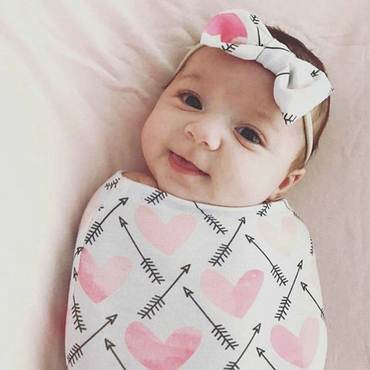 Nyfødt baby sover trygt og rolig innpakket i en myk bomullssvøpe, unisex design.