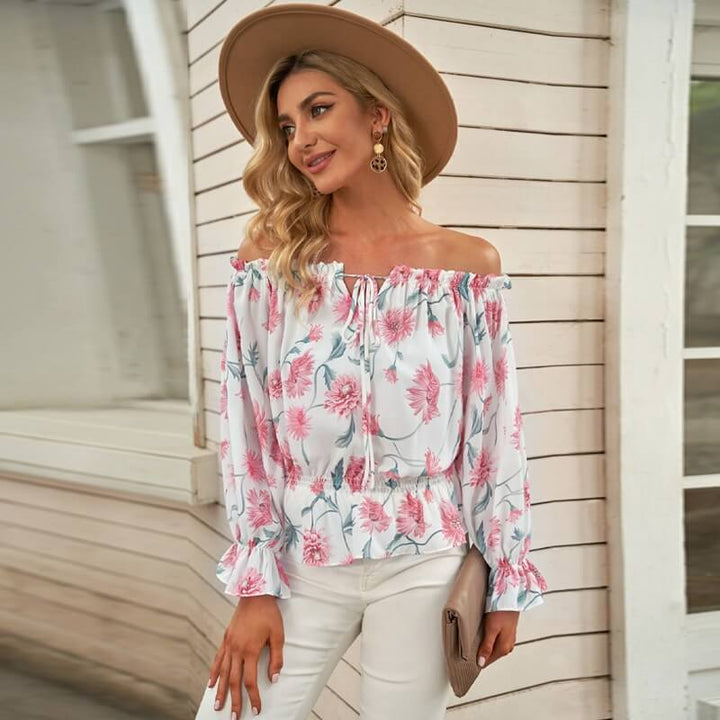 Lett og løs off-shoulder bluse med blomster og volanger. Perfekt for varme sommerdager og avslappet stil.
