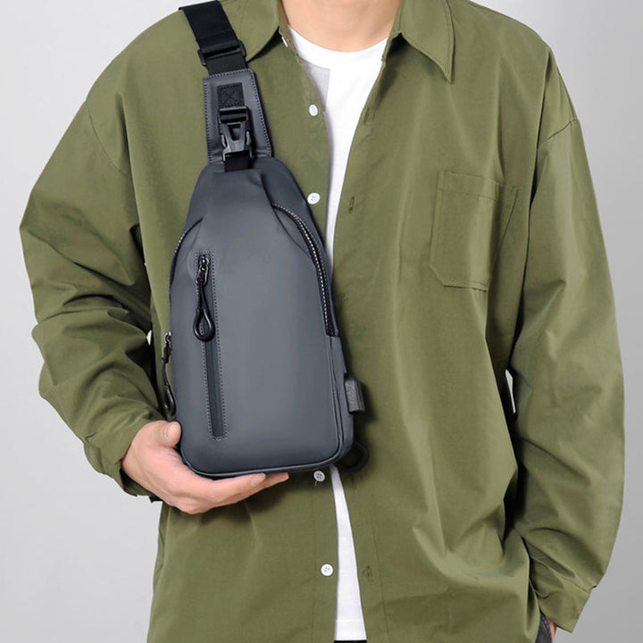 Mørk unisex vanntett skulderveske med diskret USB-ladeport. Stilrent design.