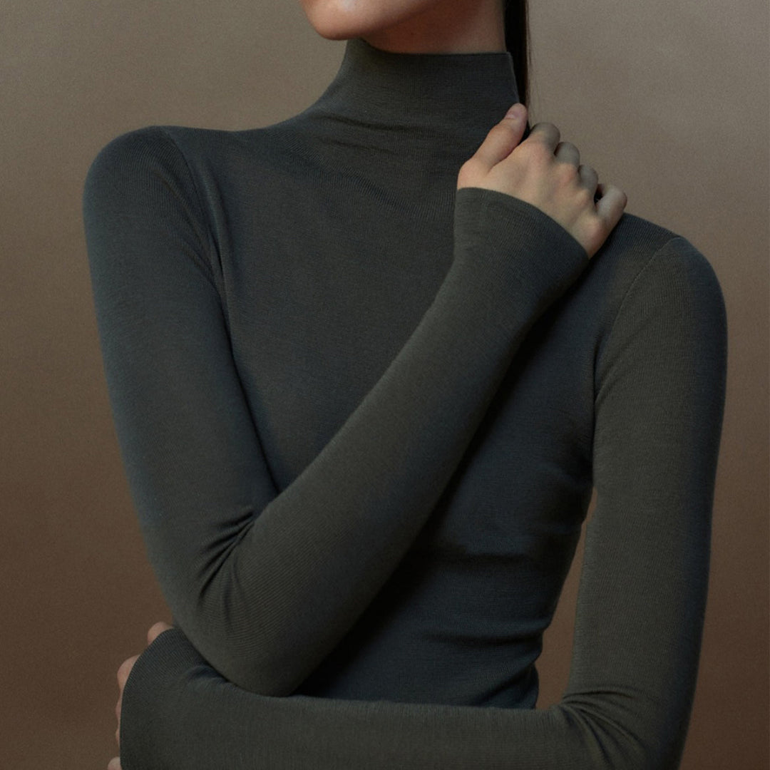 Elegant dametopp: ensfarget, langermet og strikket med høy hals, for en sofistikert look.