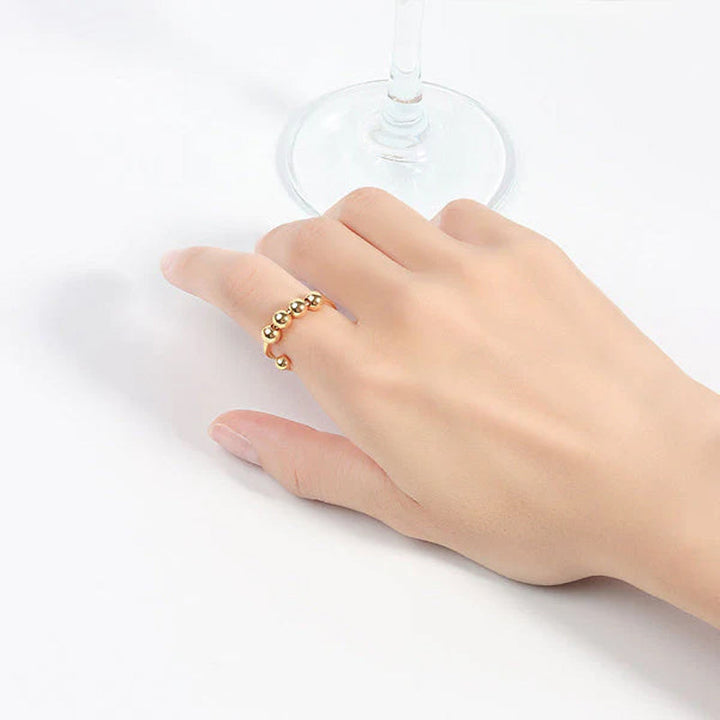 Elegant angstring med 4 glatte perler som roterer, perfekt for stressmestring og fokus.