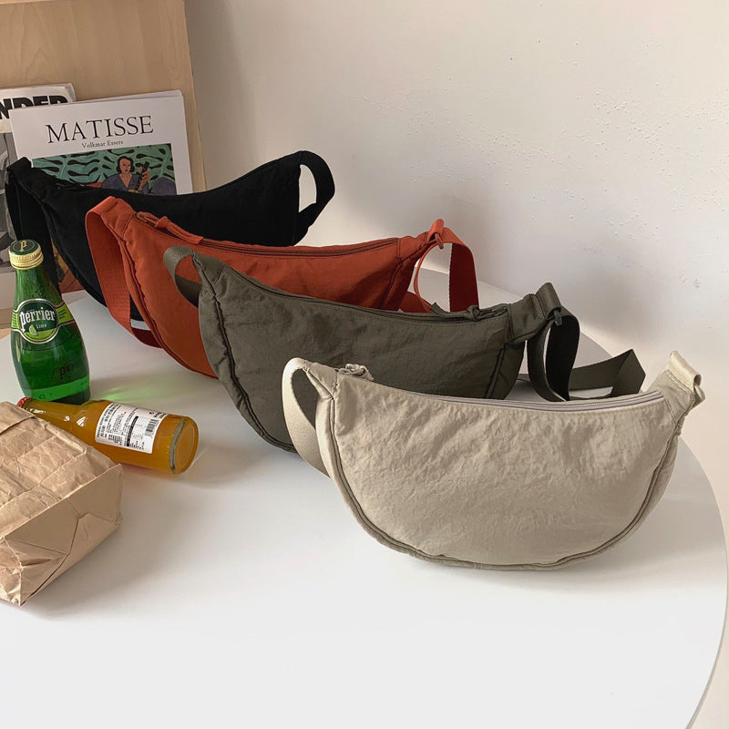 Unisex modell bærer en stilig halvmåne crossbody-veske i nylon, passer perfekt til urbant antrekk.