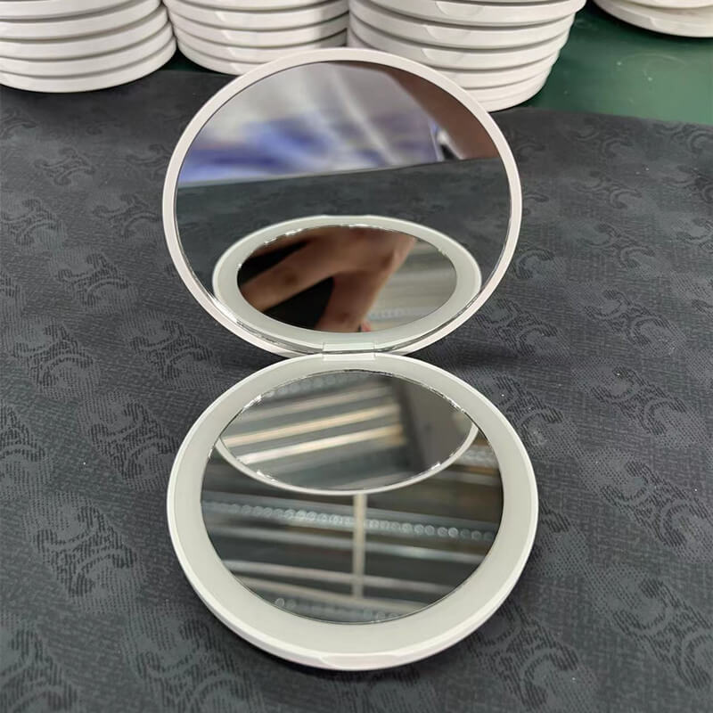 Rundt LED-håndspeil med innebygd lys og zoomfunksjon, flott for detaljert sminke og hudpleie.