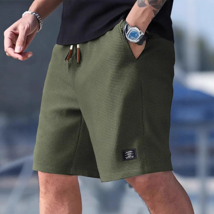 Detaljbilde av sidelomme på komfortabel herre sportsshorts. Robust design, perfekt for oppbevaring.