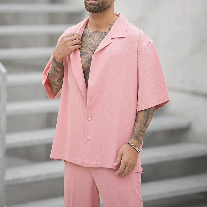 Mann i rosa todelt sommer fritidssett. Komfortabelt kortermet antrekk i polyester, stilfullt for herre.