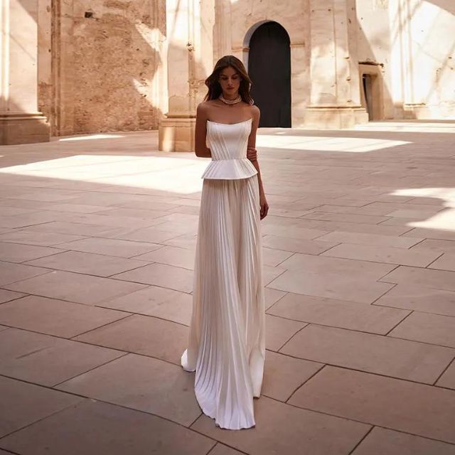 Modell i hvit off-shoulder aftenkjole. Plissert kjole som fremhever en feminin og sofistikert stil.