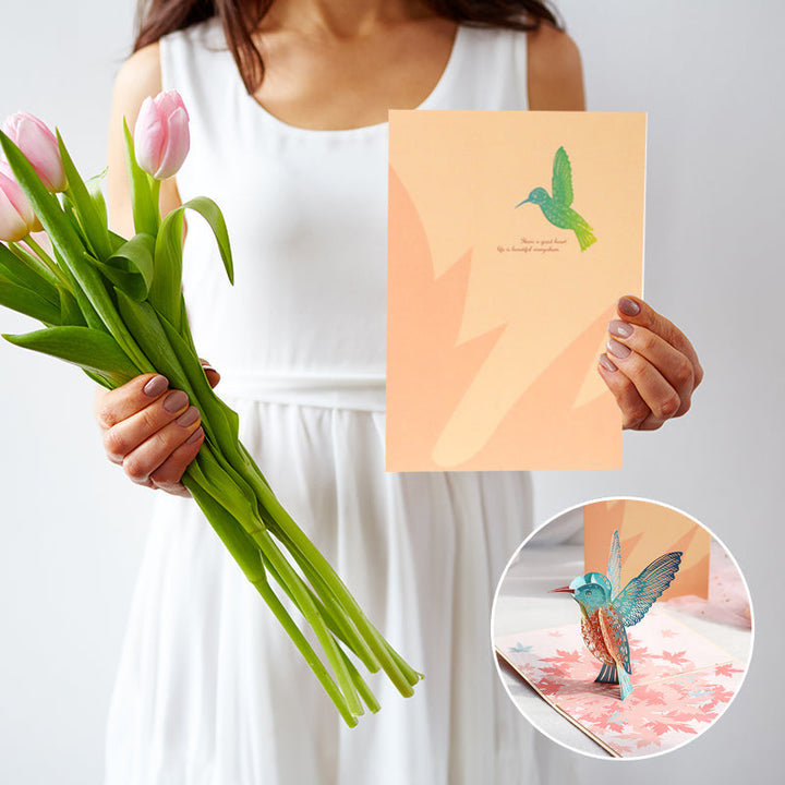 Vakkert pop-up kort for morsdag. Detaljert kolibri og liljeblomster popper opp. Ideell gave til mamma.