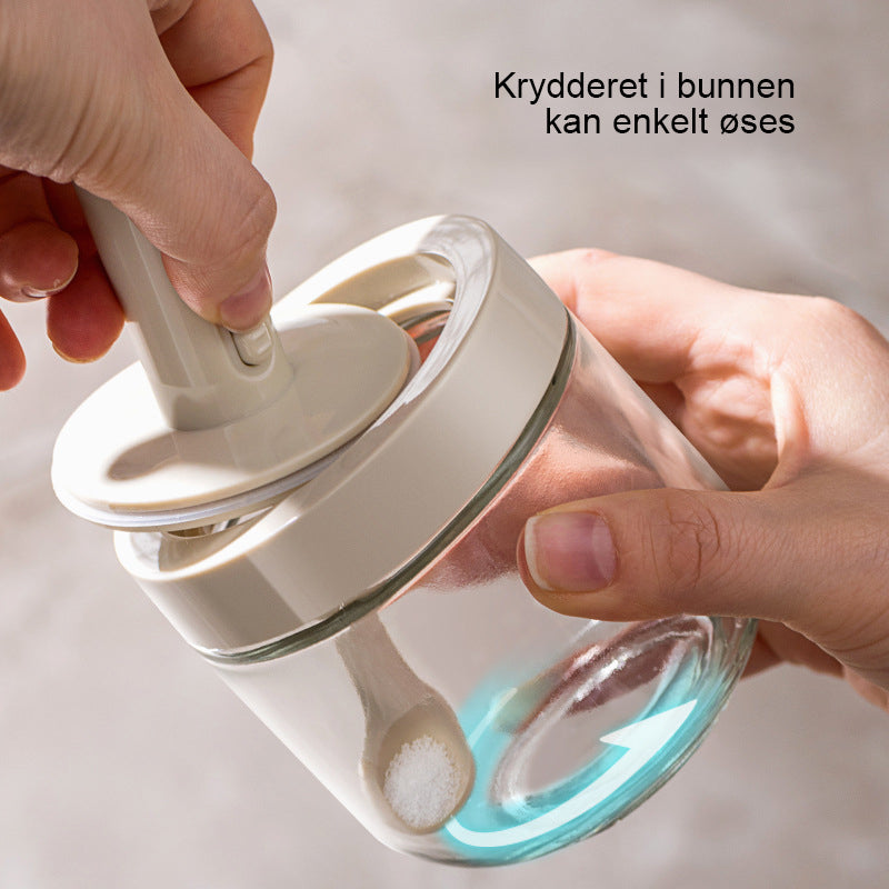 Praktisk krydderkrukke med justerbar skje for enkel dosering og ryddig matlaging.