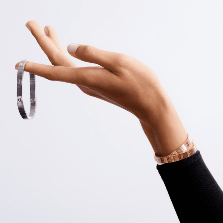 Unisex 'Love' armbånd båret på håndleddet. Elegant, minimalistisk og fleksibelt smykke.