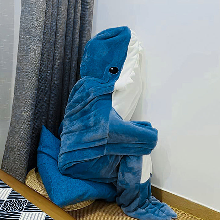 Fullfigur av person i myk, blå hai-onesie av fleece, klar for kos eller temafest.