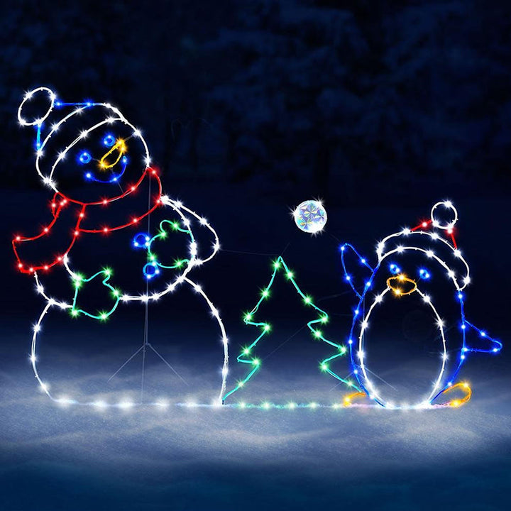 Utendørs animert juledekorasjon viser snømann og pingvin i snøballkamp. Lyser opp vinterhagen.