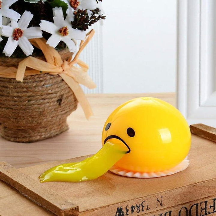 En hånd klemmer en eggeplomme stressball, viser den myke teksturen. Effektiv for avkobling og ro.