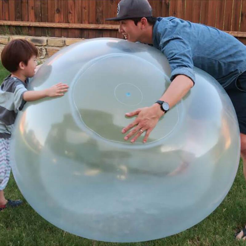 Familie nyter utelek med en oppblåsbar gigantball; barnas sommeraktivitet og moro for alle.