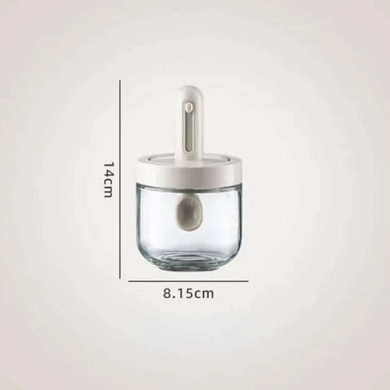 Moderne krydderkrukke i glass med justerbar skje, perfekt for et organisert og stilfullt kjøkken.