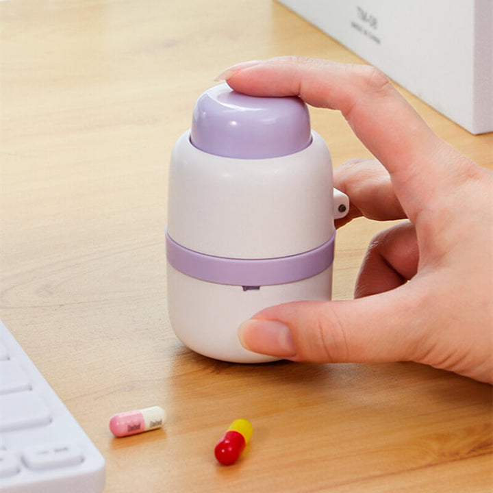 Hvit bærbar pillekutter med integrert oppbevaring for enklere håndtering av medisiner og vitaminer.