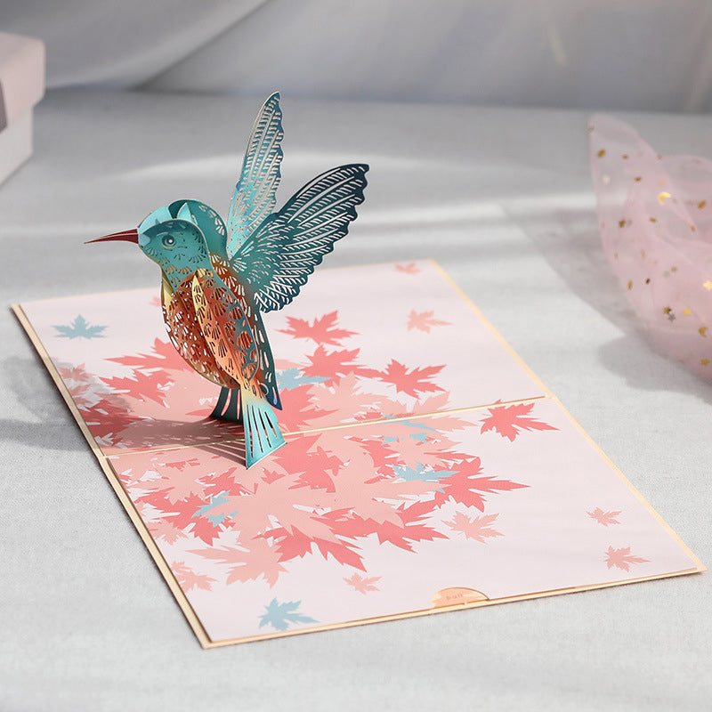 Morsdagskort med 3D kolibri og fargerike liljeblomster som popper opp. Unik blomsterhilsen.