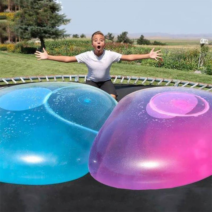 Barn løper og leker med en stor oppblåsbar bubble ball i hagen, perfekt for sommerlek og moro.