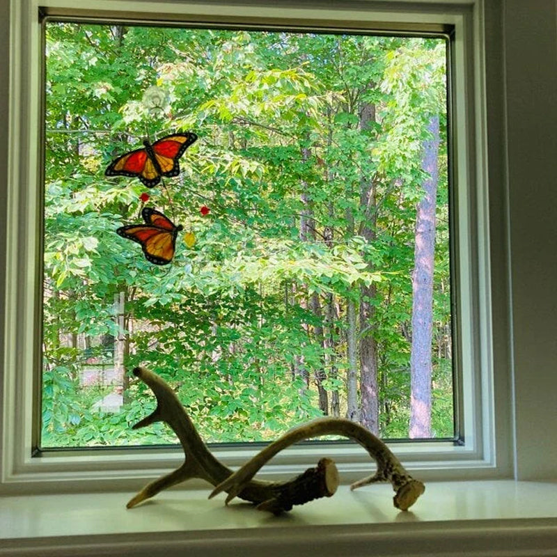 Nærbilde av farget glass monarksommerfugl dekorasjon, reflekterer sollys og skaper glød.