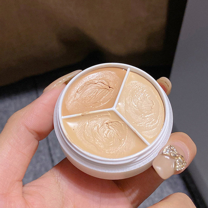 Nærbilde av den kremete teksturen i Trefarget Concealer. Glir lett på huden for langvarig dekk.