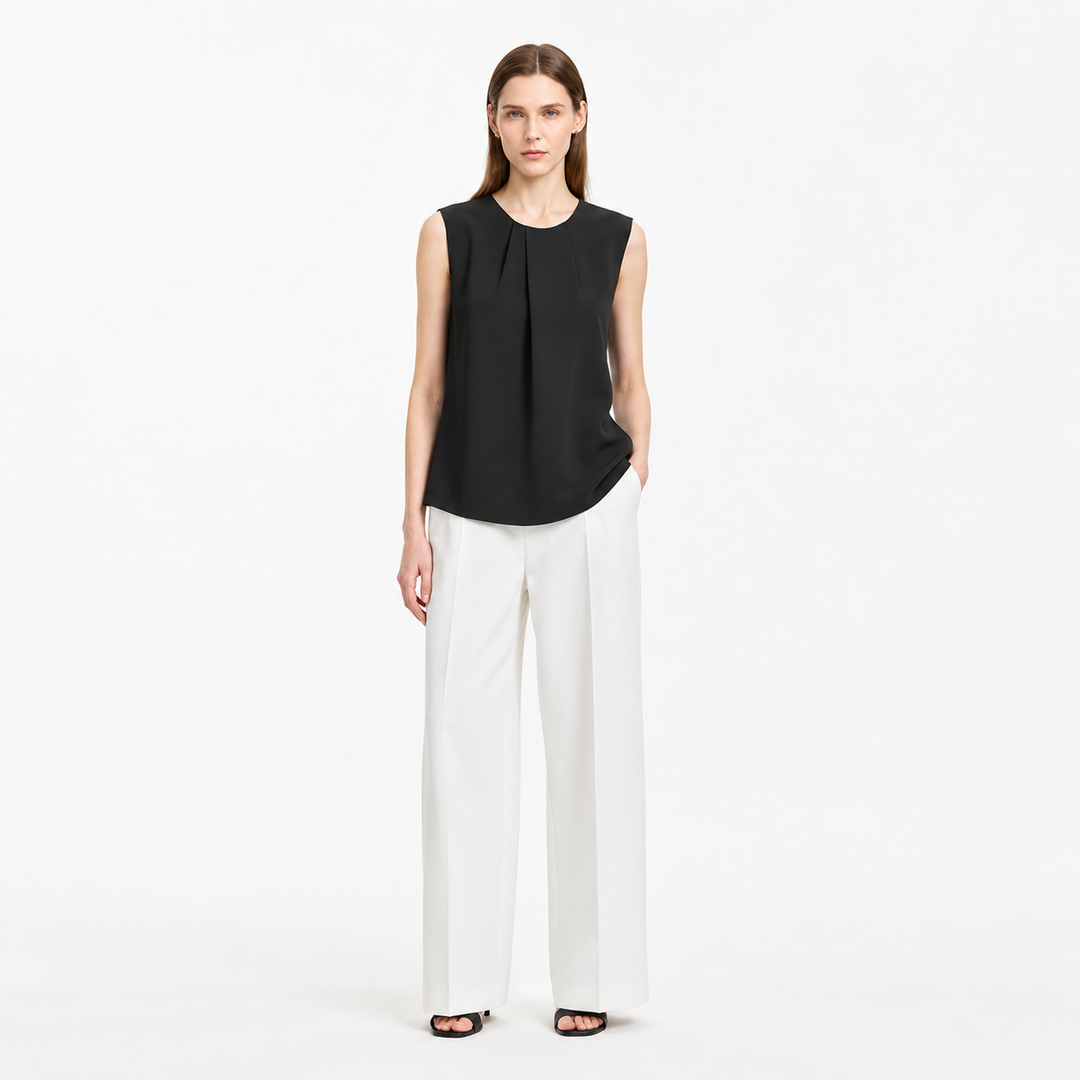 Plissert damebluse med asymmetrisk design. Ermeløs sommertopp, ideell for varme dager og kontoret.