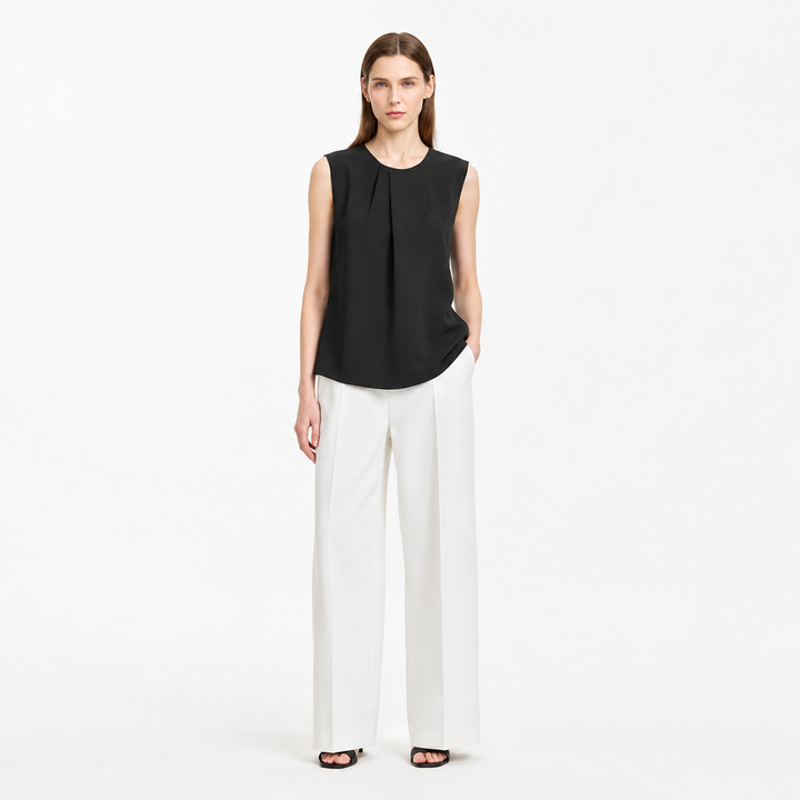 Plissert damebluse med asymmetrisk design. Ermeløs sommertopp, ideell for varme dager og kontoret.