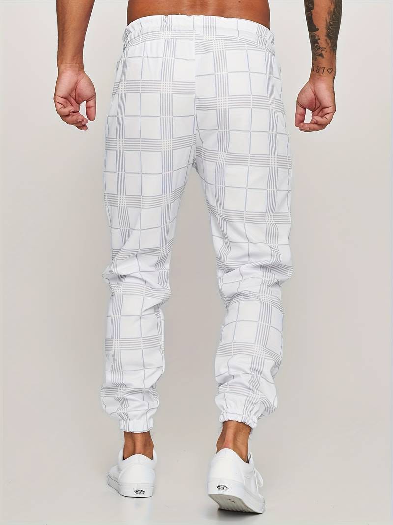 Ung mann i trendy herre rutete joggebukse, viser avslappet urban stil.