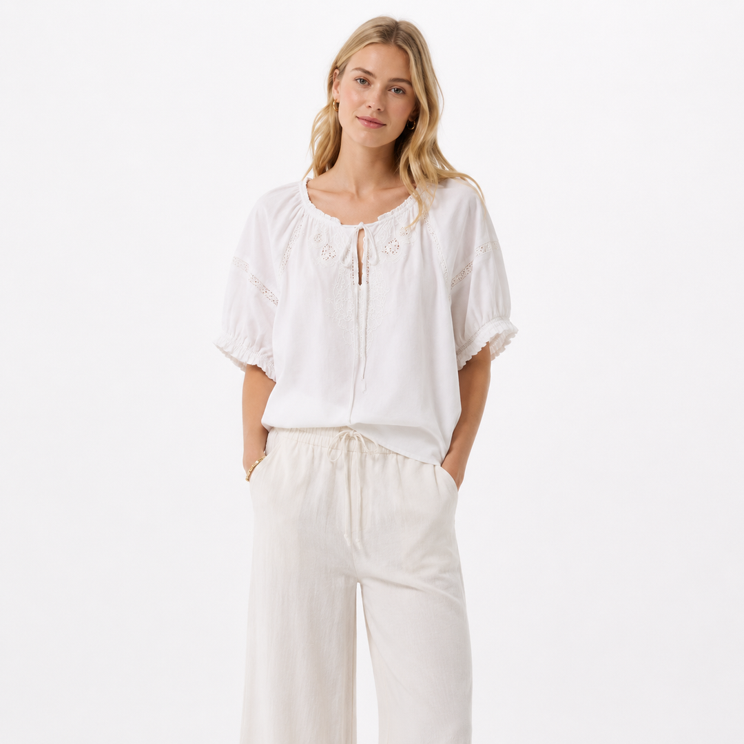 Elegant hvit damebluse med broderier og trendy puffermer, perfekt for sommerlige dager eller fest.