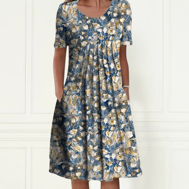 Ryggvisning av en kortermet damekjole med blomstertrykk. Ledig passform i lett polyester.
