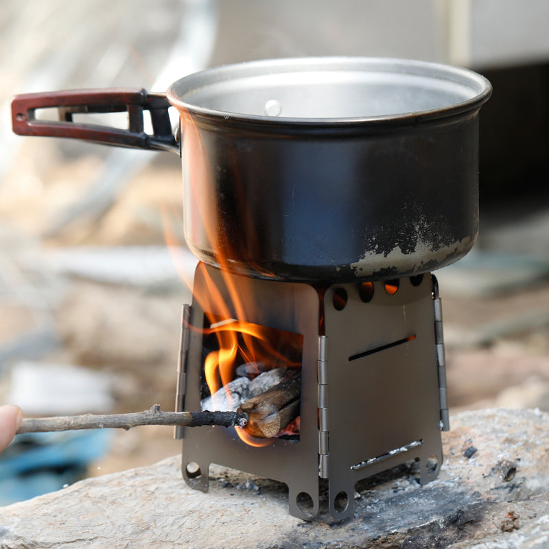 Bærbart grillsett i rustfritt stål med grillrist og ben, klar for grilling på campingtur eller utflukt.