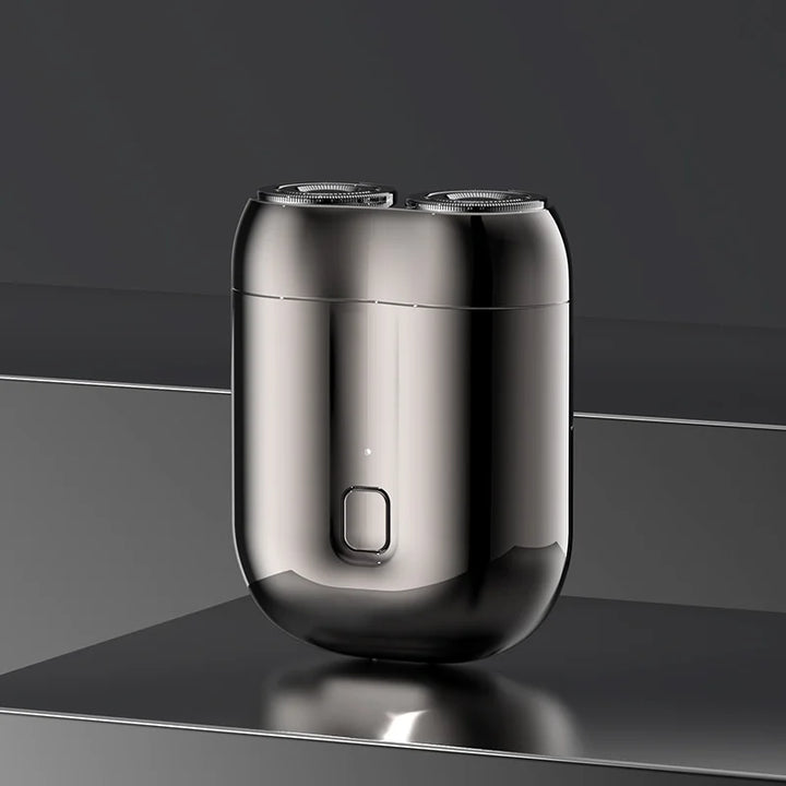 Mini barbermaskin vist i hånden, fremhever kompakt design og bærbarhet for herrepleie.