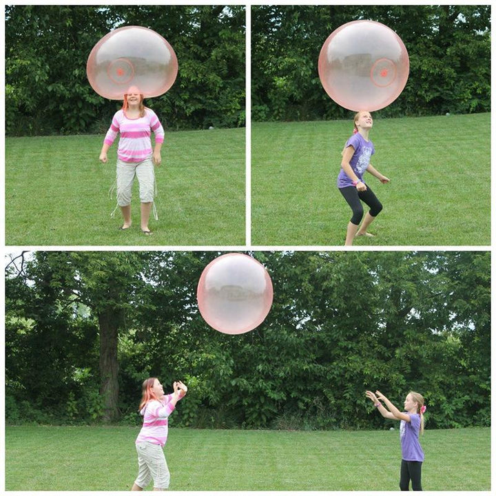 To barn som ler og kaster den store oppblåsbare bubble ballen; sommerlek og aktivitet.