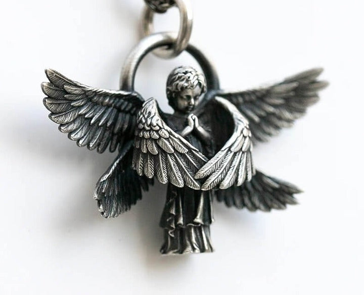 Nærbilde av detaljert engleanheng i sølv på halskjede. Symbolsk beskyttelse, tidløst unisex design.