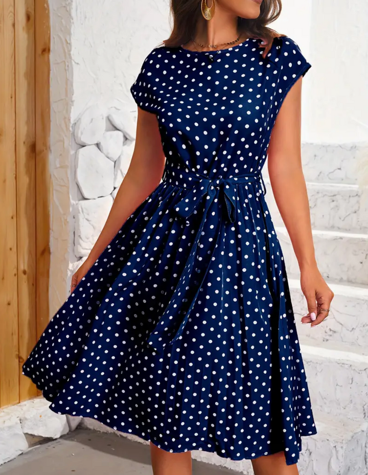 Kvinne i elegant retro polka dot svingkjole, viser frem tidløs vintage stil. Ideell som fest- og hverdagskjole.