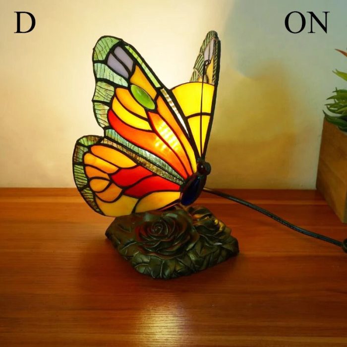 Sjarmerende dekorativ bordlampe med glassmaleri og retro sommerfugl design. Skaper vakkert lys.