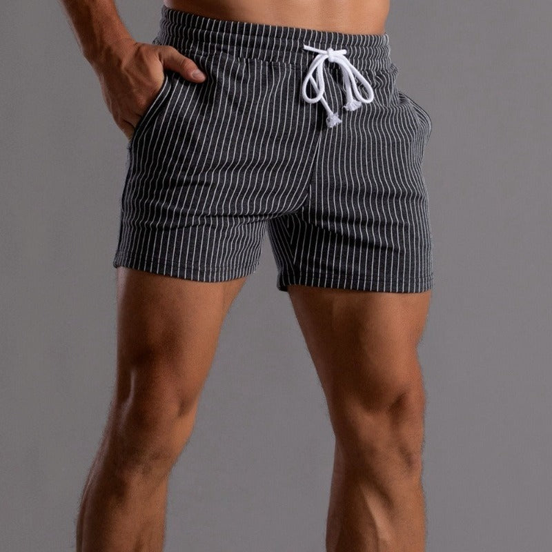 Mann spaserer langs strandpromenaden, iført blå herre sommerstrandshorts.