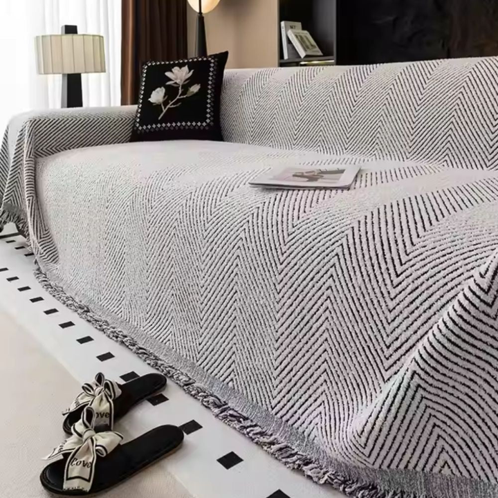 Beskyttende møbeltrekk til sofaen. Vendbart design med fiskebensmønster. Vaskbart tekstil for langvarig bruk i stuen.