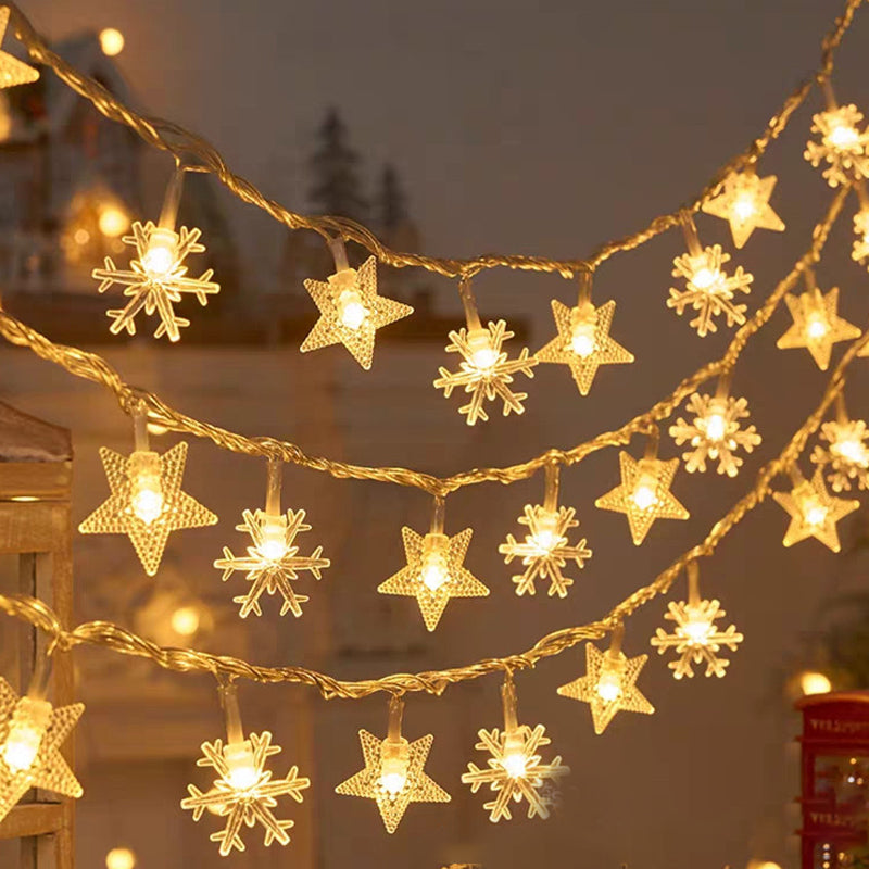 Varmgule LED snøfnugglys drapert over busker utendørs, vakker hagedekorasjon til jul.