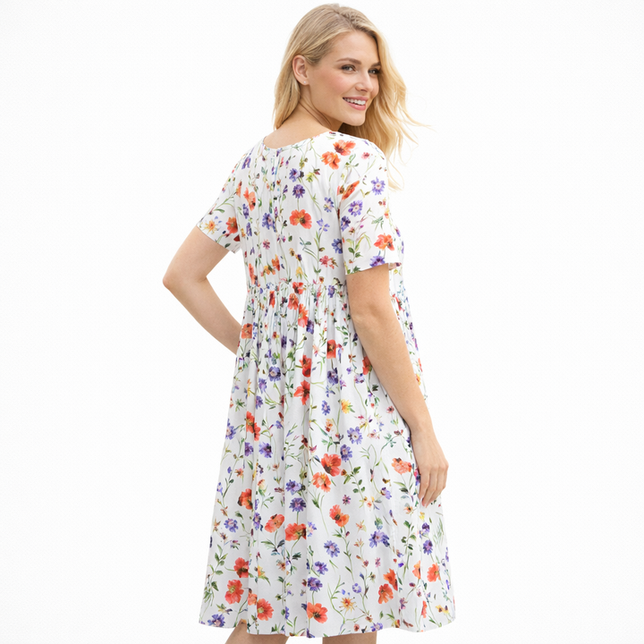 Frisk vårkjole med feminine blomster, vidt skjørt og korte ermer. Komfortabel damekjole med rund hals.