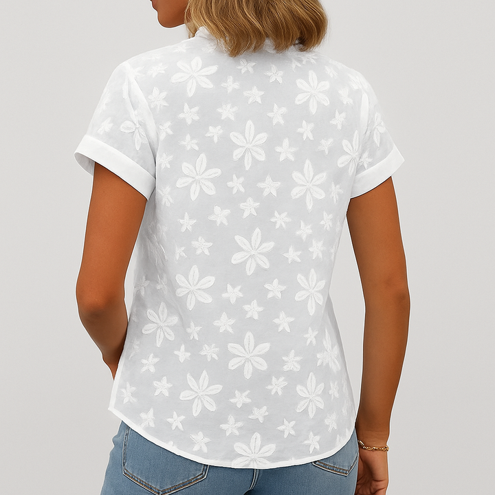 Feminin hvit kortermet topp med blomstret mønster og v-hals, en komfortabel og elegant sommerbluse.