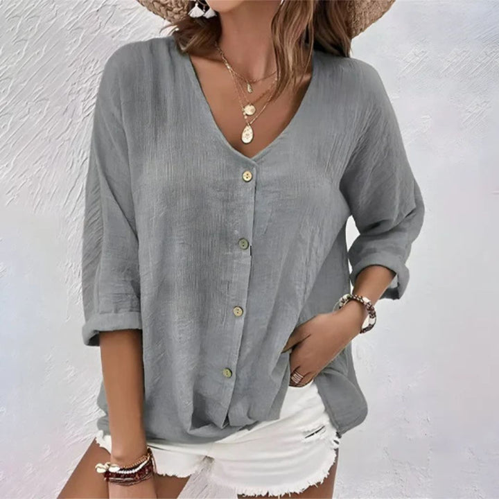 Damebluse med V-hals og knapper, vist på modell. Elegant og avslappet stil for jobb og fritid.