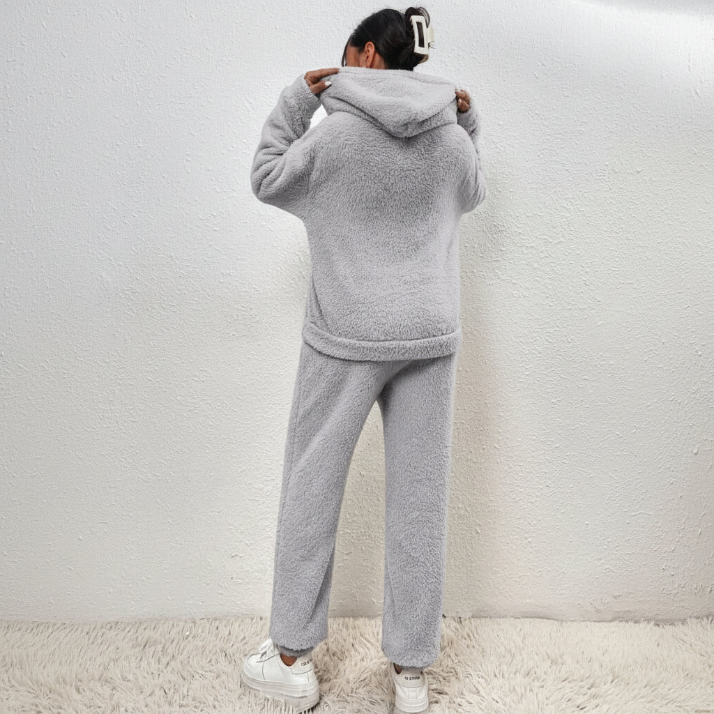 Kvinne som slapper av i koselig dame loungewear sett av teddystoff, med en varm kopp, symboliserer vinterkomfort.