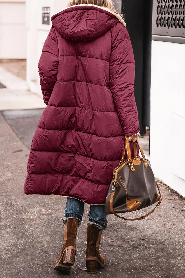 Dame iført dobbelsidig parkas vinterjakke med hette, viser passform og stil. Holder varmen i kulden.