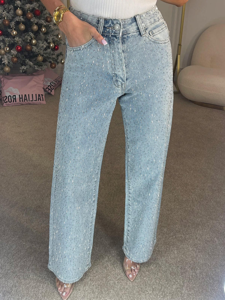 Nærbilde av glitrende detaljer på mørkeblå damejeans med høy midje. Moderne og chic stil.