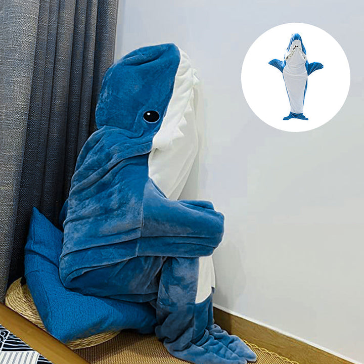 Lekent bilde av en person som tøyer seg i en blå hai-onesie av fleece. Varm og komfortabel pyjamas.