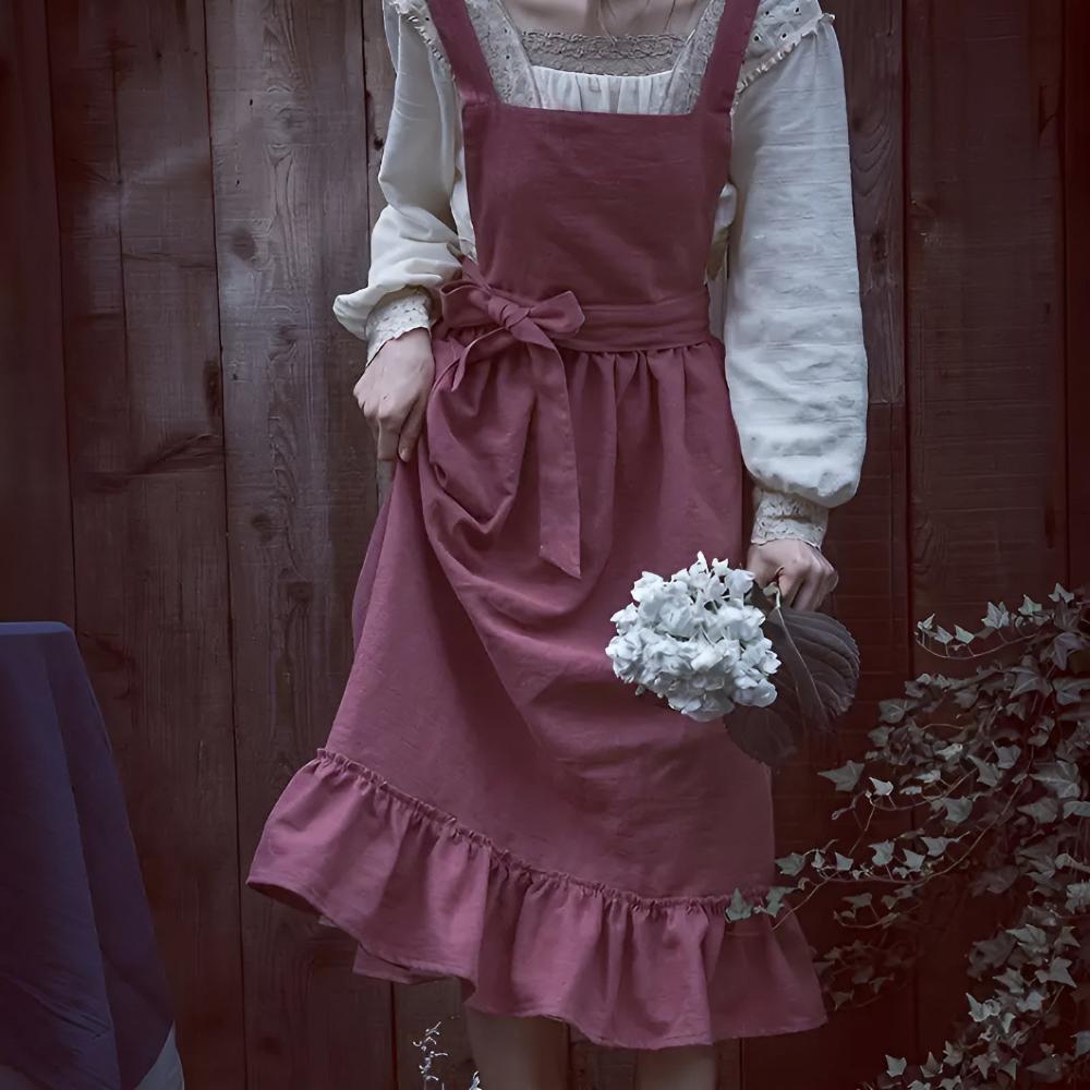Vintage-inspirert kjøkkenforkle for kvinner med praktisk lomme og justerbare stropper. Tilgjengelig i beige.
