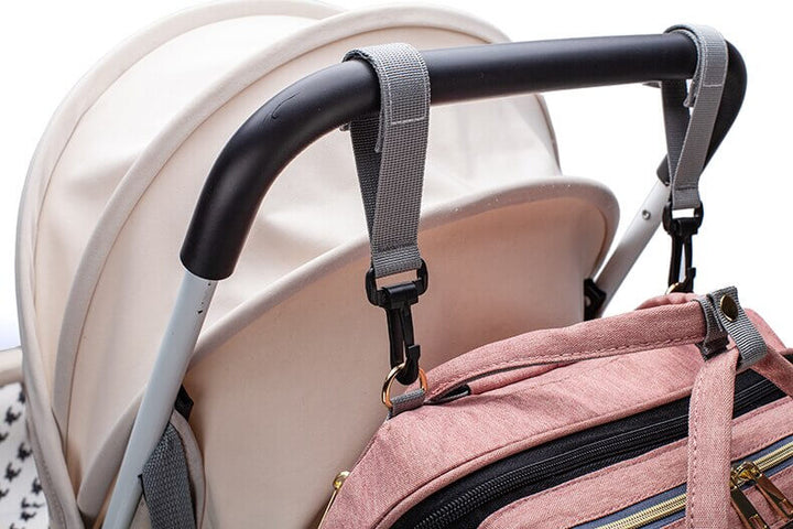 Foreldre bærer unisex reiseveske/ryggsekk med bærbar babyseng og stelleveske for babyutstyr.