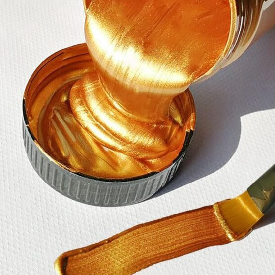 Hånd påfører miljøvennlig metallisk akrylmaling på et dekorativt objekt for hobbybruk.