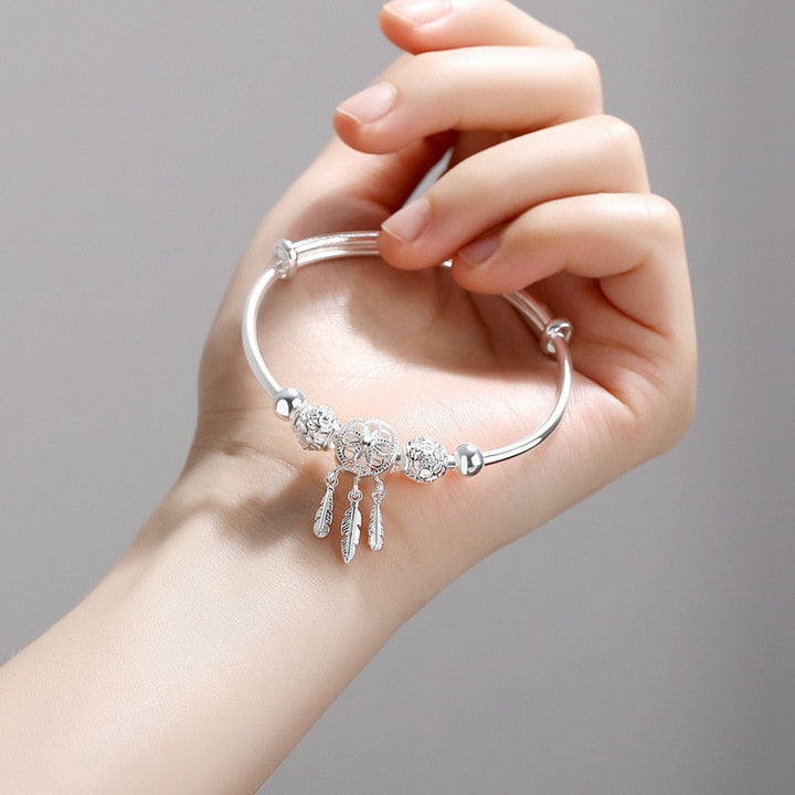 Kvinne bærer et elegant sterlingsølv drømmefanger armbånd på håndleddet.