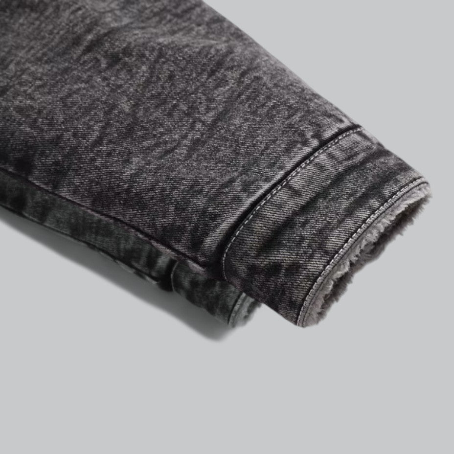 Detalj av denimjakke for herre, viser stofftekstur og knapper. Slitesterk og varm overgangsjakke.