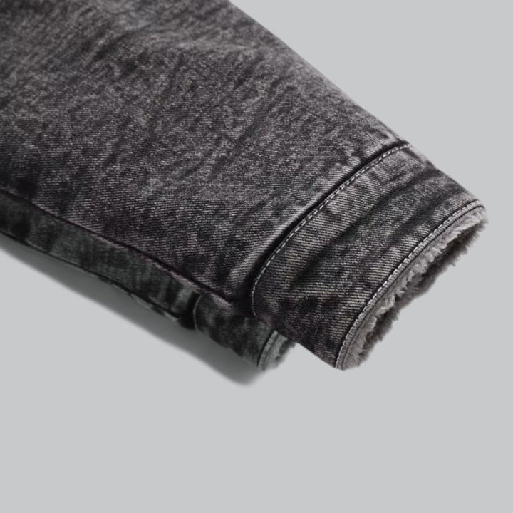 Detalj av denimjakke for herre, viser stofftekstur og knapper. Slitesterk og varm overgangsjakke.